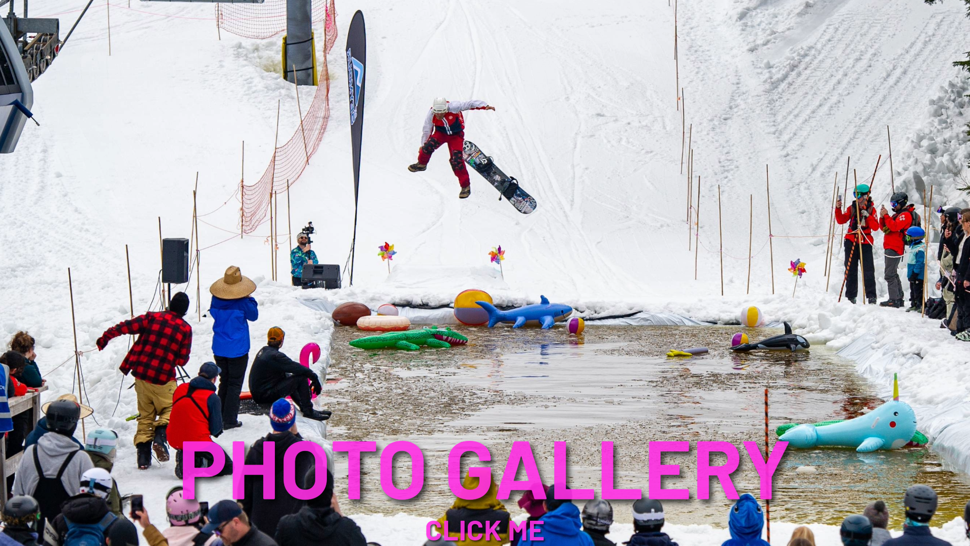 Snowboarder jumps over snowy pond as spectators watch.