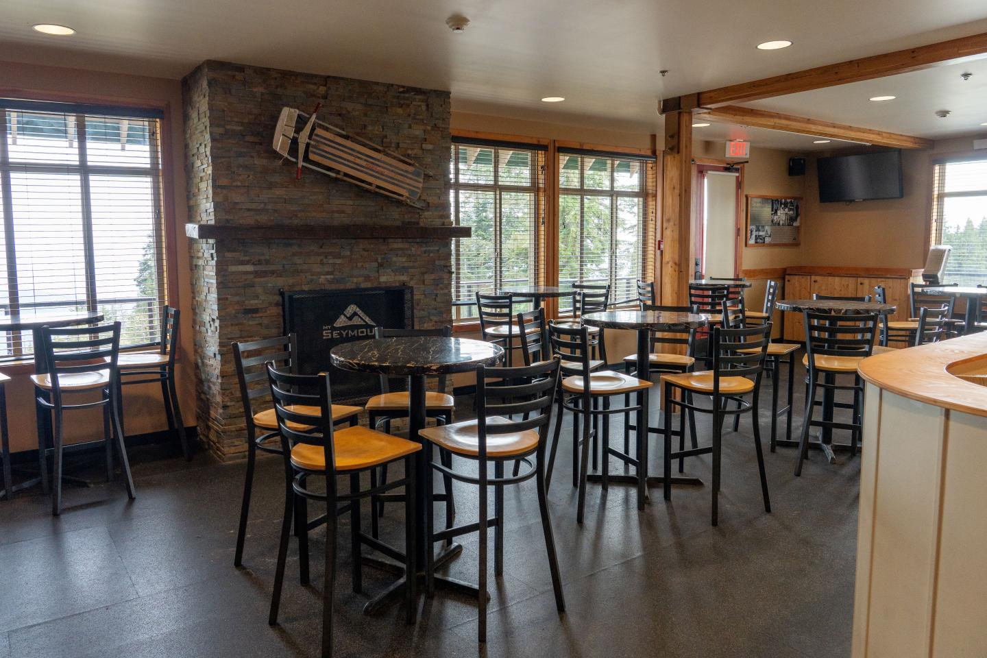 Cozy café with wooden tables, chairs, and a stone fireplace.