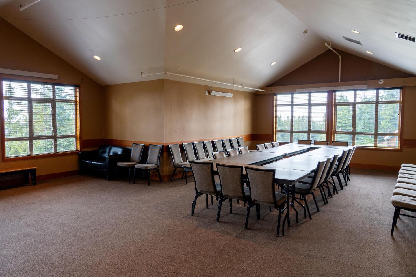 Large conference room with a central table, chairs, and large windows. Quiet and spacious.