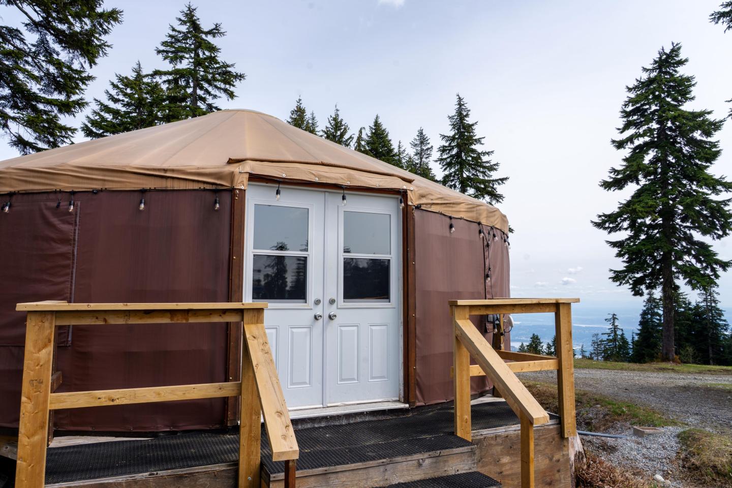 Yurt in a wooded area with trees and a cloudy sky.