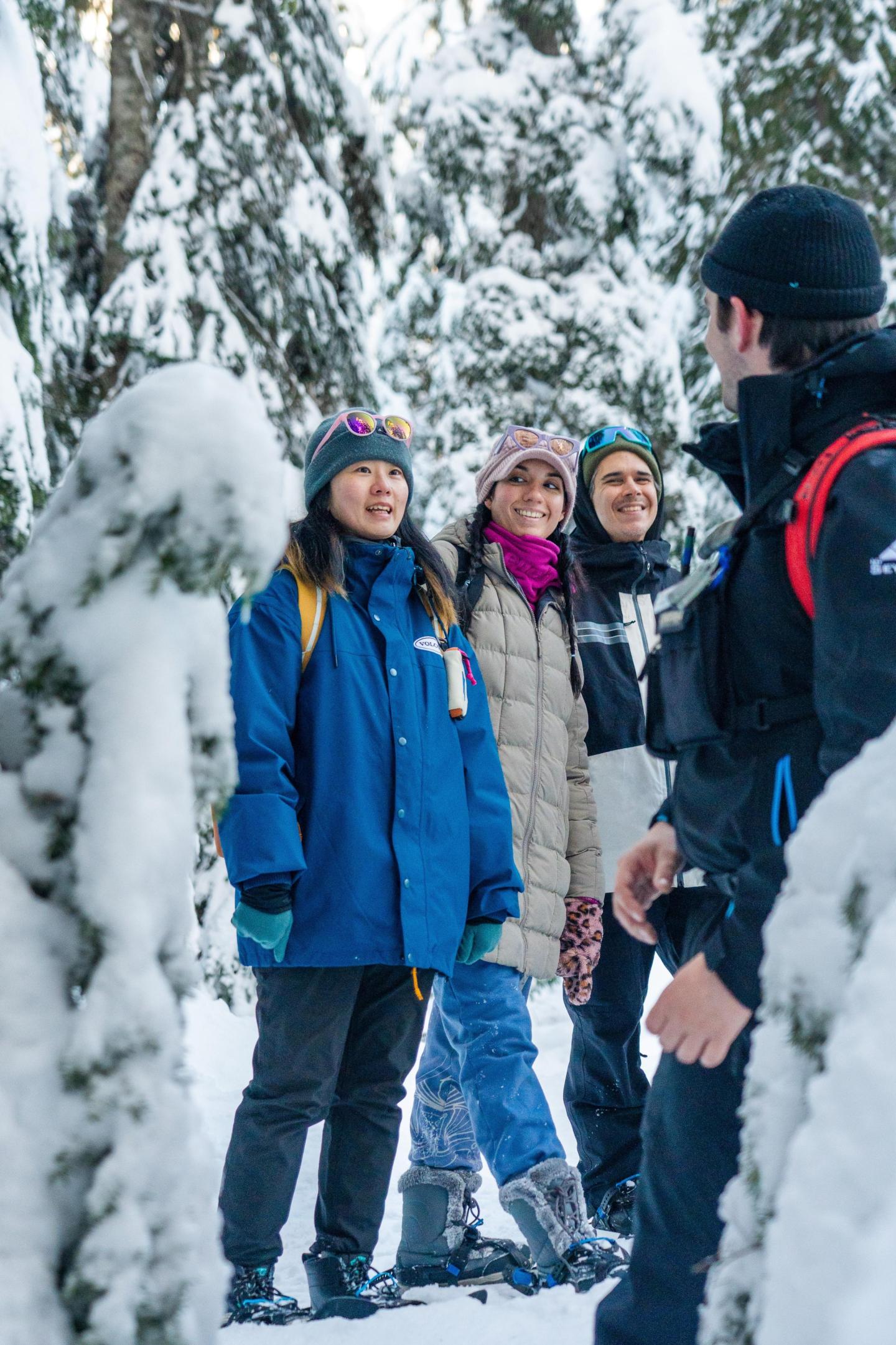 Snowshoe guide leads a group of smiling people in the forrest