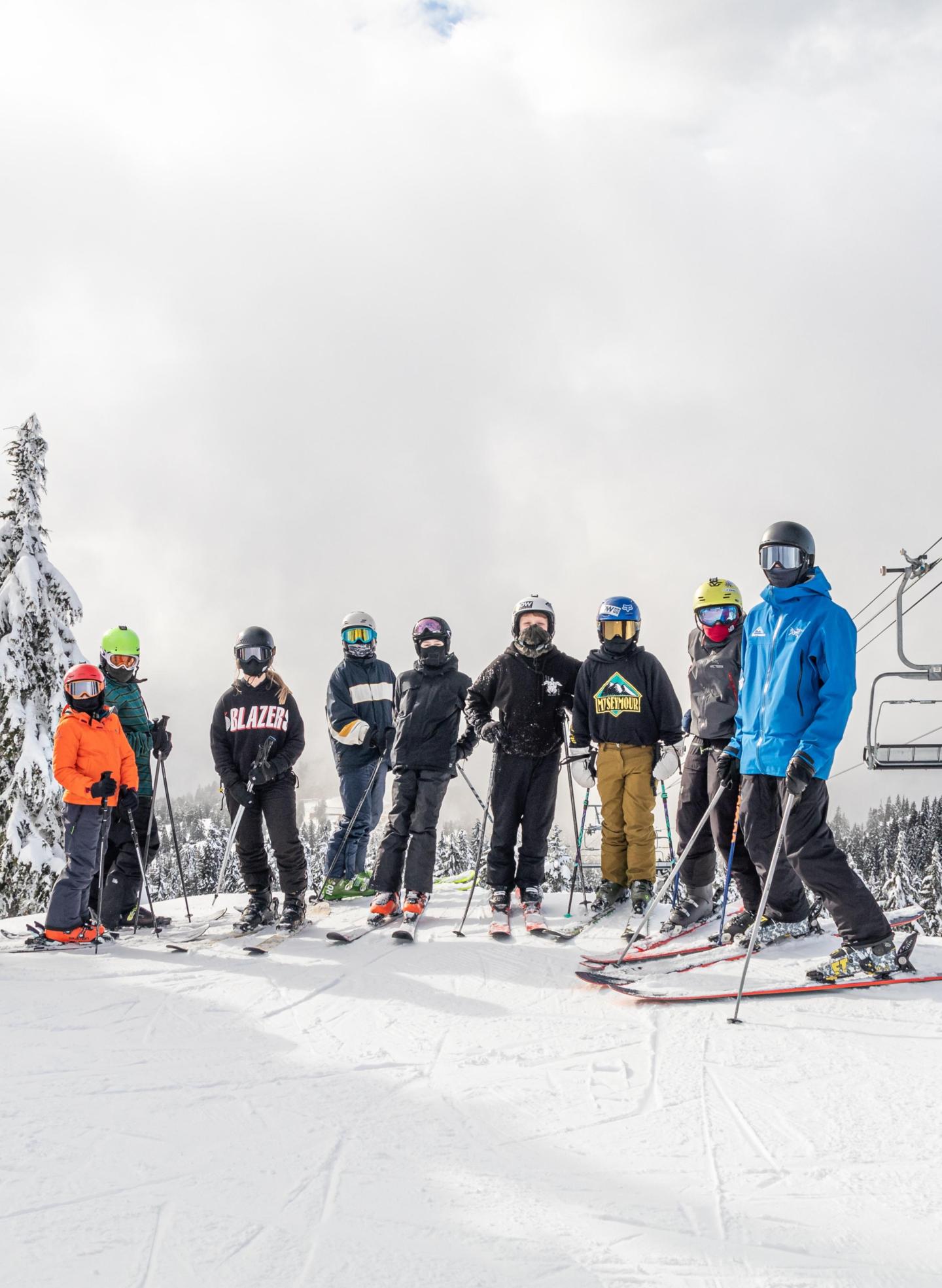 A group of skiers on a snowy slope, cloudy sky above.