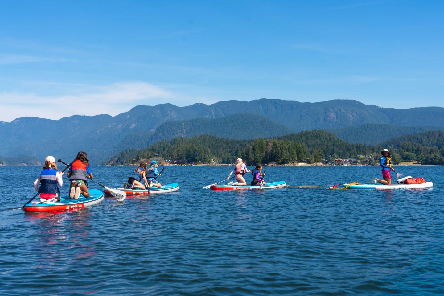 People paddleboarding on a lake with mountains in the background.