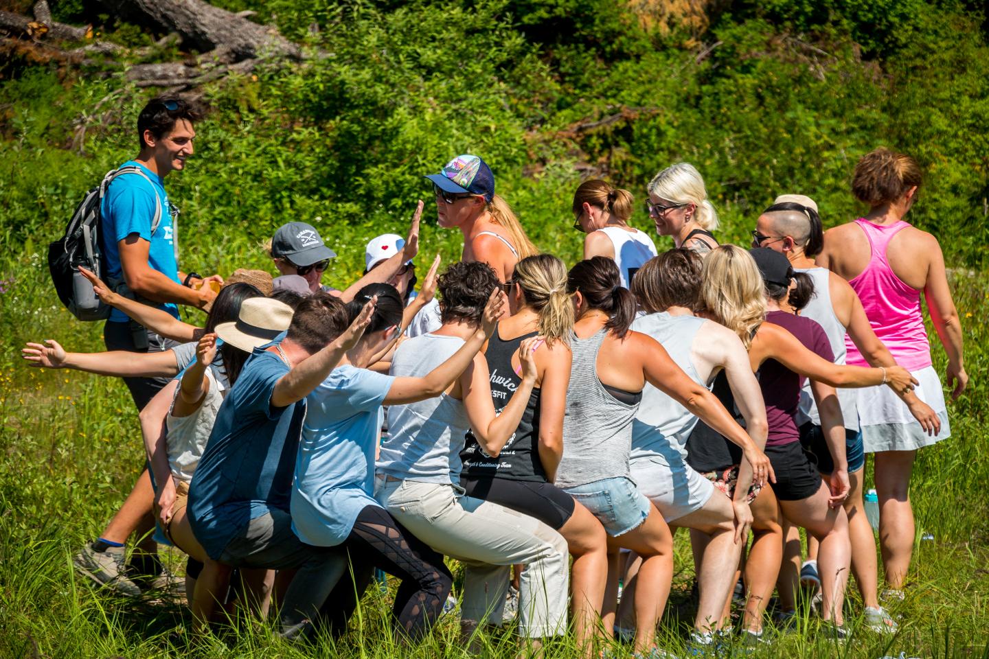Group of people forming a circle, playing a team-building game outdoors.