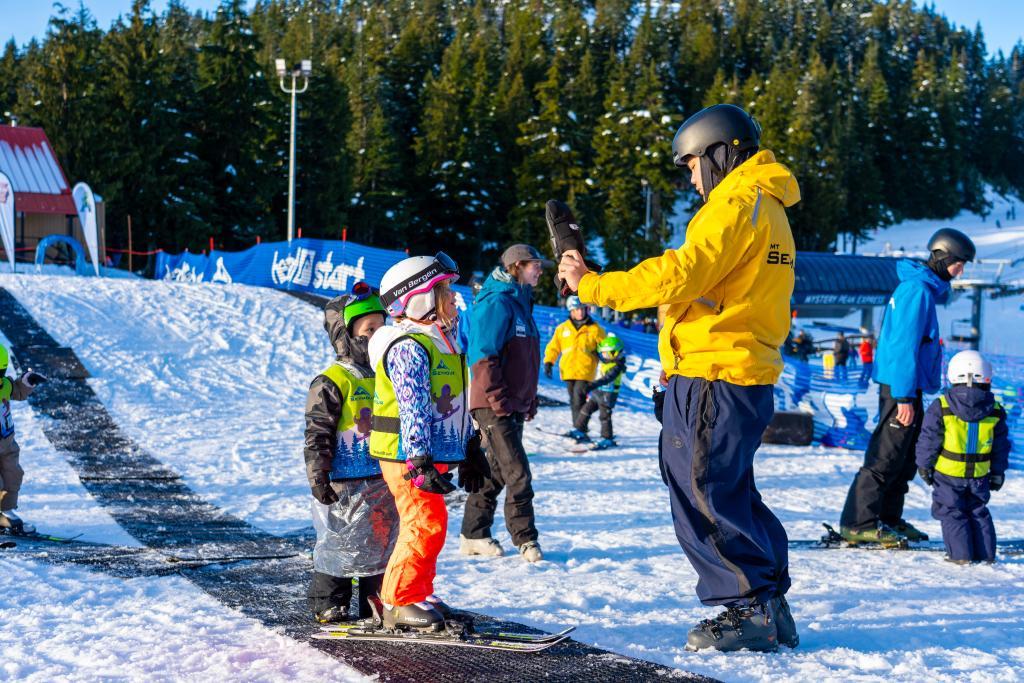 Ski instructor guides children on a snowy beginner slope.